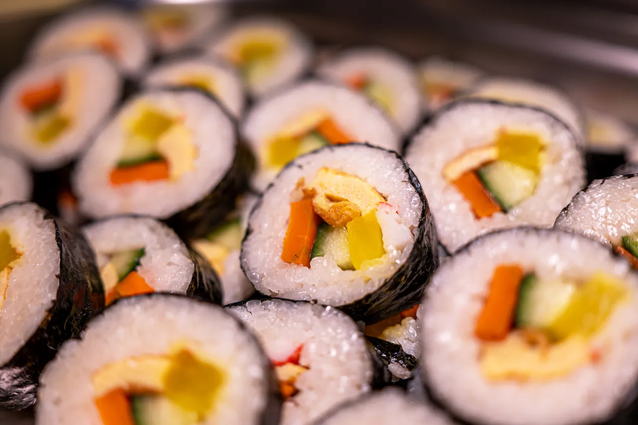 Nahaufnahme frisch geschnittener Kimbap-Rollen mit Ei, Karotte, Gurke und eingelegtem Rettich in Reis und Seetang.